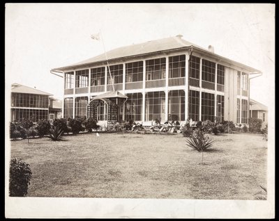 Una casa a due piani circondata da portici, con una bandiera americana che sventola; a Panama durante la costruzione del canale, 1912 da Byron Company